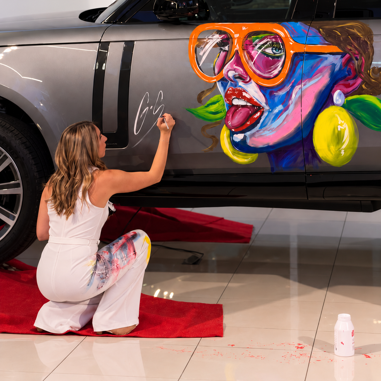 Ona Saumell pintando y firmando la carrocería de un Range Rover