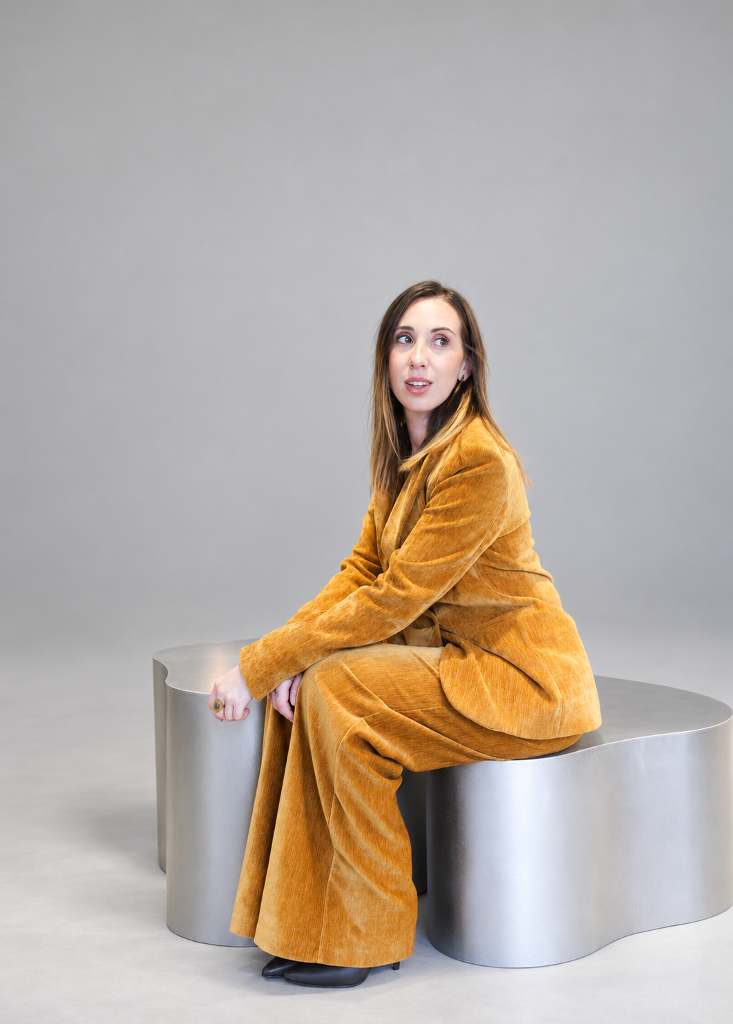 Portrait of Ona Saumell Rovira seated on a sculptural bench in a photography studio
